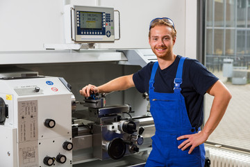 Worker or fitter posing in front of turning machine at workshop