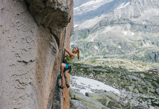 young female rock climber climbing in alpine landscape
