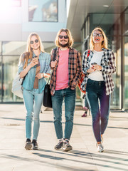 Group of student friends walking with cups of coffee having pleasant talk, sunset