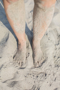 A woman's sandy feet and legs at the beach