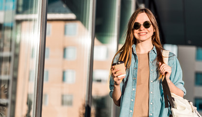 Obraz premium Hipster stylish girl wear sunglasses walk and hold cup of coffee