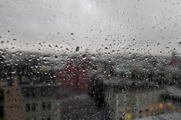 rain drop on clear glass window, reflection of blurred city and light bokeh from outside, beautiful color abstract for background