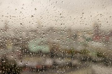 rain drop on clear glass window, reflection of blurred city and light bokeh from outside, beautiful color abstract for background