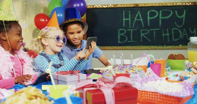 Kids looking at pictures in mobile phone during birthday party 