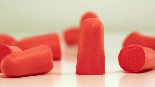 Red ear plugs rotating on white background, soft polyurethane foam. Earplugs offer hearing protection against harmful noise