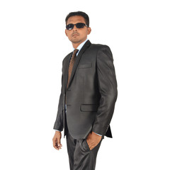 Portrait of a young businessman in black suit standing over white background