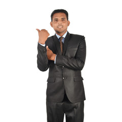 Portrait of a young businessman in black suit pointing away over white background