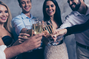 To us! Close up cropped shot of excited best friends with beaming smiles celebrating with stemware of white martini wines, in glamorous, fancy, classic outfits, enjoying company of each other