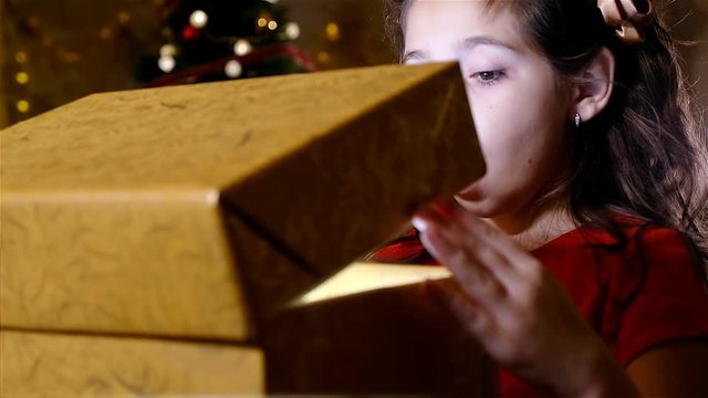 Christmas magic concept. Amazed little caucasian girl looking at magical gift in the box. Fairy particles flying out of the box