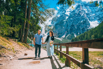 Fototapeta na wymiar Young Couple against lake, summer park. lago di braies,Dolomite,Italy. Man and woman on vacation in beautiful place.