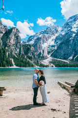 couple hold the hand stand at the end of pier at lake at sand, lago di braies,Dolomite,Italy