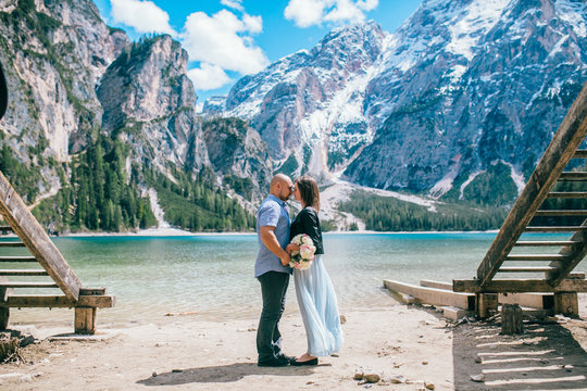 couple hold the hand stand at the end of pier at lake at sand, lago di braies,Dolomite,Italy