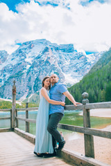 Fototapeta na wymiar Man and woman on vacation in beautiful place mountains.Young couple in love on the pier at lake, lago di braies,Dolomite,Italy.