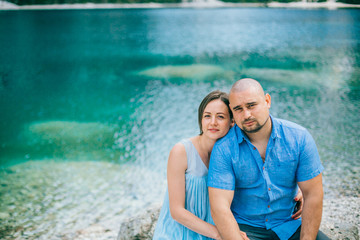 Portrait of relaxed young couple on lake braies in south tyrol, italy. Woman in long blue dress. Man in blue shirt. People in love.