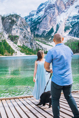 Couple with dog. Beautiful young couple playing with dog while sitting near the lake braies in south tyrol, italy