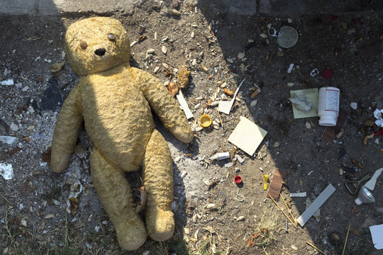 Naklejki Broken teddy bear next to a dumpster