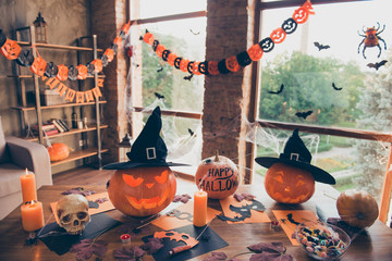 Preparation for halloween, cutted pumpkin, fall leaves, spiders nets, headwear of witch, bowl with candies on top of wooden table. Ready for feast in mystery interior. Concept of all hallows eve