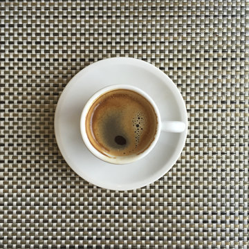 Overhead shot of espresso on a brown patterned placemat.