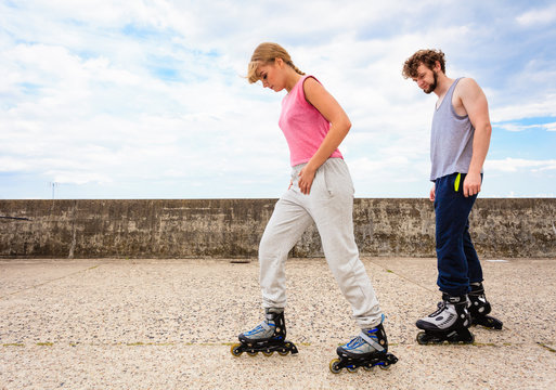 Friends learn rollerblading together have fun at park.