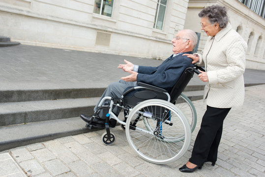 old woman woman pushes husband in wheelchair