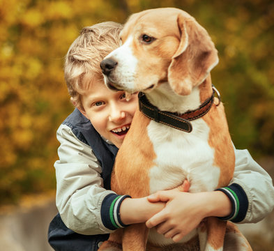 Happy smiling boy hugs his best freind beagle dog