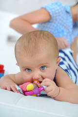 Fototapeta na wymiar small newborn baby schewing on a plastic rattle
