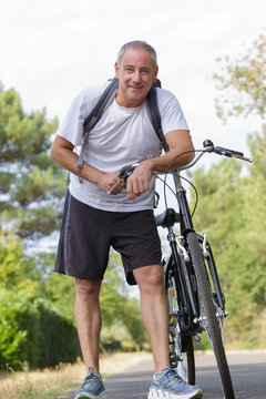 man smiling and posing with his bike in the woods