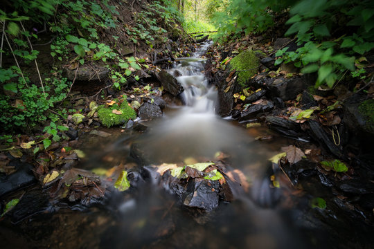 Kleiner Wasserfall eines Baches im Wald, langzeitbelichtet