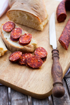 knife,  fresh bread and sausage on the table
