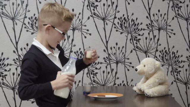Funy boy drinks milk with his friend teddy bear