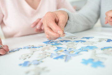 Fototapeta na wymiar women playing with jigsaw puzzle on wooden table