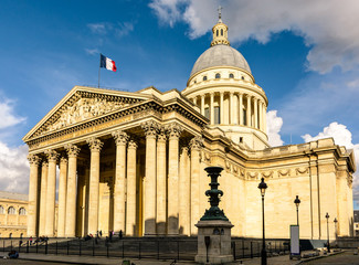 Three-quarter view of the Pantheon in Paris at sunset with the french flag flying in the wind.