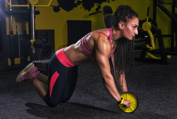 Attractive Woman Exercising With Wheel Roller For Abs On Floor In Gym As Part Of Fitness Training