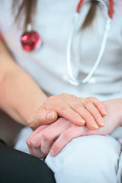 Closeup of hand on top of nurse's hand