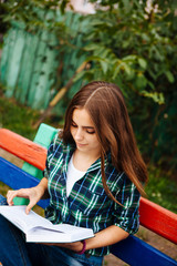 Obraz premium Beautiful girl reading book outdoors, with copy space