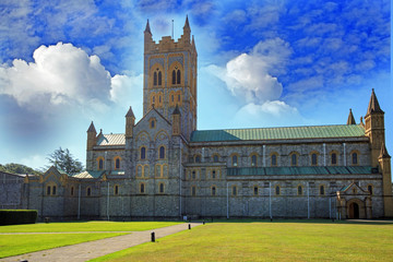 Fototapeta premium Church Cathedral against a blue cloudy sky and a lush green grass freground
