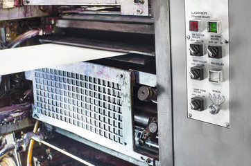 A large offset printing press running a long roll off paper over its rollers at high speed