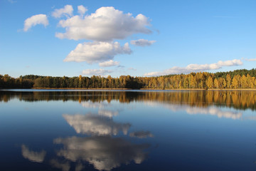 Lake in a delightful autumn forest at sunny day. Autumn trees with reflection. Russia.