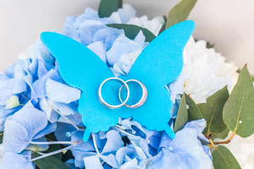 Beautiful wedding rings lie on a paper butterfly