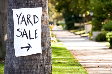 Hand painted yard sale sign with direction nailed to a palm tree.