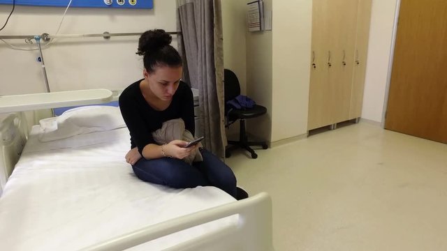 Attractive teen girl sending a text message in hospital sitting 