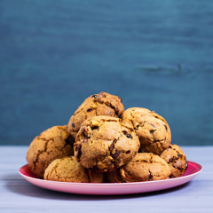 Chocolate cookies in pink plate on blue and purple background. Toned image, author processing, square format