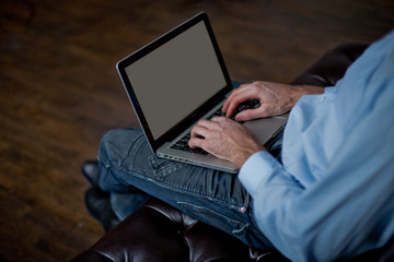 A man chooses gifts through the Internet. Shopping with laptop on Black Friday. Hands on the keyboard and blank screen to insert text.