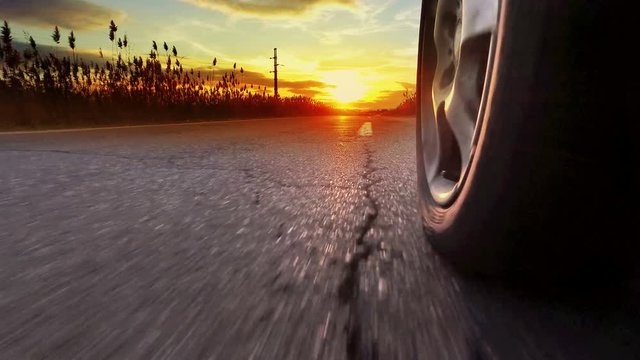 Drive on asphalt at sunset against bright setting sun with 