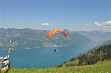 Gordijnen Gleitschirmfliegen über dem Vierwaldstättersee inmitten der Schweizer Berge in der Zentralschweiz / Bunter Paragleiter / Gleitschirm fliegt über den See, Schweiz © hachri