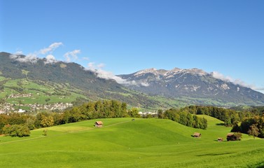 Blick &uuml;ber gr&uuml;ne Wiesen und W&auml;lder auf die Gemeinden Alpnach und Alpnachstad und den Berg Pilatus im Hintergrund - Schweiz