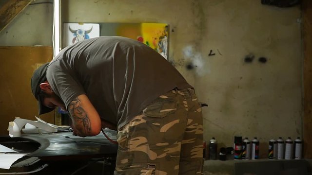 Garage artist makes painting airbrushing on the hood of the car