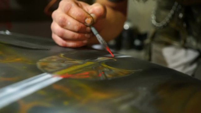 Artist paints using a brush on the hood of car