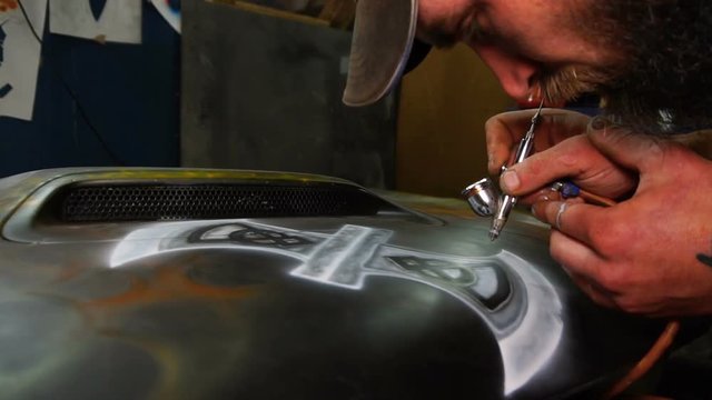 Man paints with a spray gun on the hood