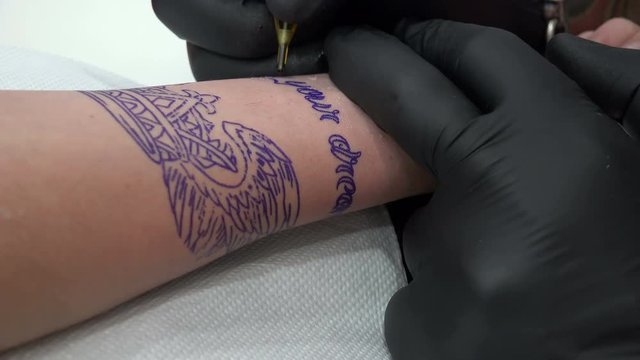 Master tattoo draws the paint on the clients hand closeup. 